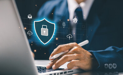 A business professional works on a laptop with a digital shield and lock interface, representing cybersecurity protection, data security, privacy control, and enterprise IT defense systems.
