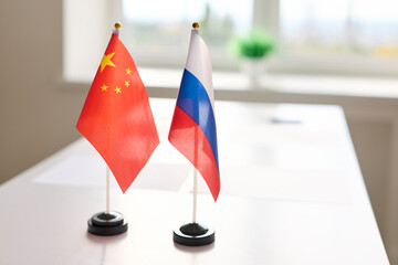 Flags of China and Russia on meeting table. Compact desk flags stand side by side in a conference...