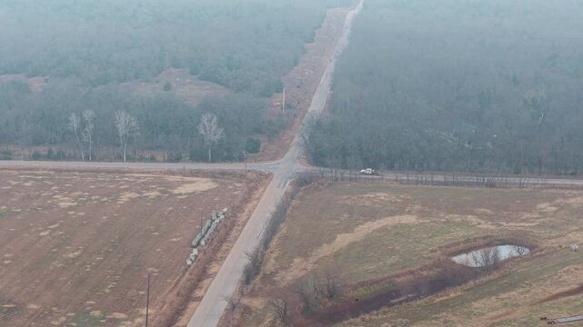 Aerial view of a truck driving through a rural road intersection surrounded by farmland. Suitable for transportation, rural infrastructure, agriculture, and countryside projects.