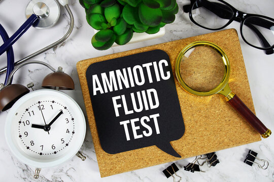 Amniotic Fluid Test text with alarm clock, calculator and stethoscope on marble background