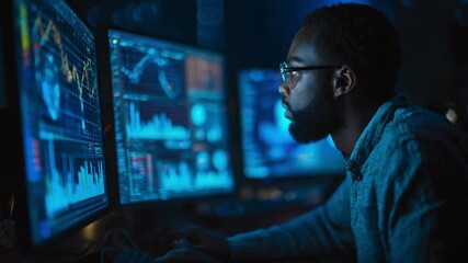 Focused data analyst monitoring financial charts on multiple computer screens - Powered by Adobe