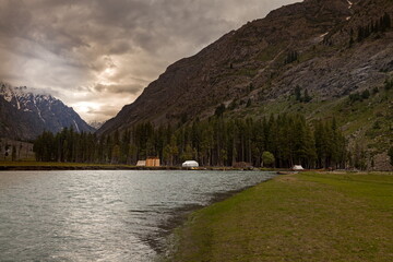 View of still lake mirroring the towering mountains and dense evergreen forest under a brooding sky, a serene landscape, Kalam, Khyber Pakhtunkhwa, Pakistan.