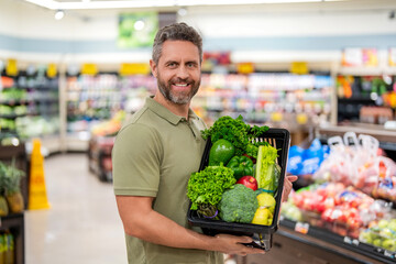 Healthy lifestyle. Organic food basket. Man in grocery store. Man shopping with vegetable basket in supermarket. Grocery consumer. Man shopping at grocery store