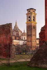 Turin, Italy. View of the bell tower and dome of the Basilica of Turin and the Chapel of the Holy Shroud seen through ancient Roman wall remains at sunset in the historic city center.