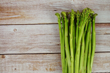 Bunch of fresh green asparagus stems on wooden background