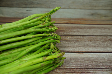 Bunch of fresh green asparagus stems on wooden background