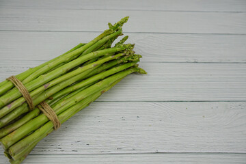 Bunch of fresh green asparagus stems on wooden background