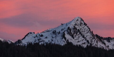 Snow-covered alpine peak under pink sunset sky