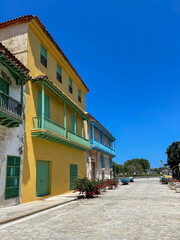 Fototapeta premium Vibrant colors colonial buildings with balconies in Old Havana, Cuba. Cobblestone streets and clear blue sky