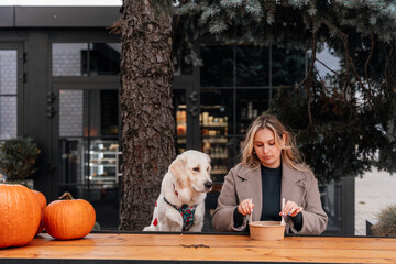 Young woman mixing takeaway salad with golden retriever at city cafe table