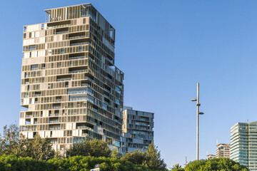View of a modern architectural marvel rises with geometric precision against the clear blue sky, a symphony of steel and glass, Barcelona, Catalonia, Spain.