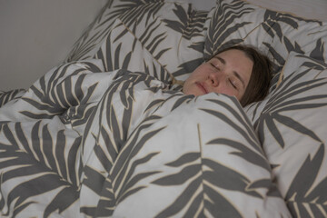 Person sleeps under a patterned blanket in a cozy bedroom during the night