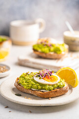 Toast with avocado, feta cheese, eggs, herbs and seeds with lemon slices on white background. Healthy eating and wholesome Breakfast