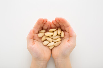 Little child opened palms holding almond nuts on light gray table background. Closeup. Point of view shot. Top down view.