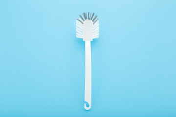 New white toilet cleaning brush on light blue table background. Pastel color. Closeup. Top down view.	