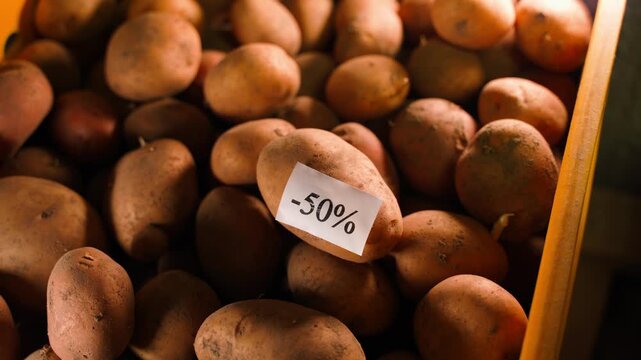 A minus 50 percent sticker is stuck on potatoes, close-up. Discounts on potatoes before the season