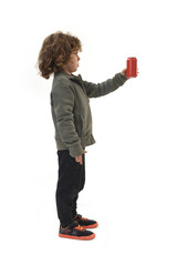 side view of a child standing and holding a can of soda on a white background