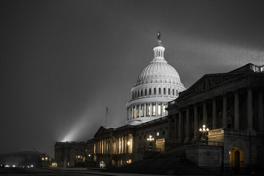 View of the Capitol Building emerges ethereally from the darkness, lit by spotlights against the night sky in Washington DC, Washington DC, United States.