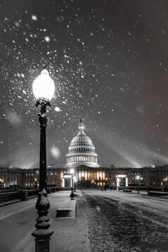 View of a snowy night casts a monochrome spell over the Capitol Building, illuminated by a vintage lamp post in Washington, D.C., Washington DC, United States.