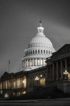 View of the United States Capitol Building standing majestic against a monochrome sky, its illuminated dome a beacon of democracy, Washington DC, United States.