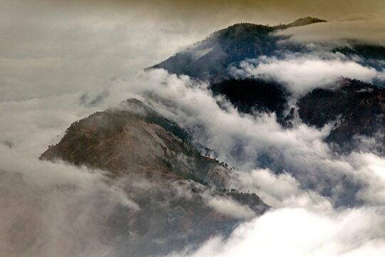 View of peaks shrouded in ethereal clouds, with dramatic lighting and textures, creating a serene yet powerful scene, Muzaffarabad, Azad Kashmir, Pakistan.