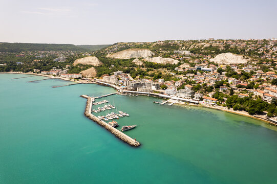 Aerial view of the turquoise waters meet the rugged coastline, cradling the quaint harbor and the distant white cliffs, Balchik, Dobrich Province, Bulgaria.