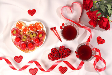 Valentine's Day food, heart of fresh canapes with salami, caviar, cheese and grapes for a buffet with roses, red wine, red hearts for the festive table, banner for advertising or invitation at the bar