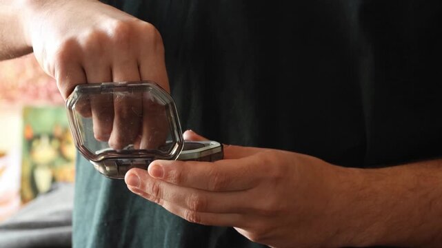 Close-up of man hands opening pill organizer container and taking out vitamins or medications. Daily health routine. Close up