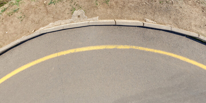 view from above on texture of asphalt road surface with cracks on turn in the road