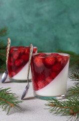 Festive Dessert Panna Cotta with strawberry in two glasses on green background