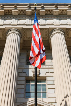 The American flag in front of the Government Building with columns in Washington. View from below.