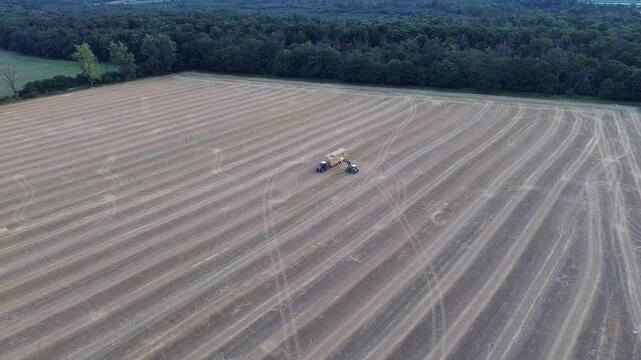 Harvested field with straw bales, tractor and trailer near Weiterstadt, Hesse, drone video