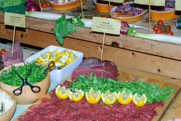 Rustic gourmet charcuterie display with bresaola beef slices, arugula and lemons on a wooden table, ideal for buffet, catering and Italian cuisine themes.