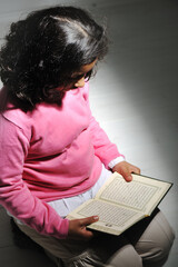 little muslim girl is rading a holly koran