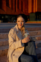 A young girl with a cup of takeaway coffee. Lunch break from school or work on the street.