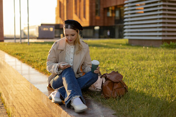 A young girl sits on a green lawn with a phone in her hands