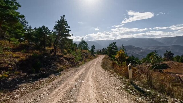 Off-road driving in 4WD vehicles on dirt roads among mountains and hills at high speed. First-person perspective. Shot with an action camera without motion blur in autumn.