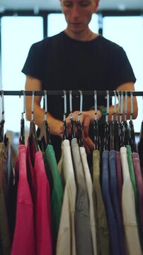 A man chooses a T-shirt, the process of choosing clothes, vertical shooting