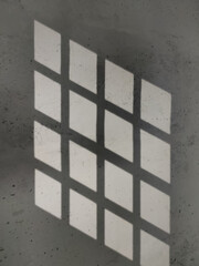 Shadow from lattice windows on a gray wall