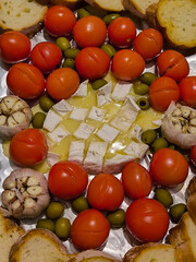 Baked Camembert cheese with tomatoes, garlic, olives, and baguette
