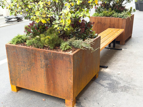 Rustic metal planters with wooden benches on urban street