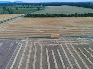 Harvested field with straw bales, tractor and trailer near Weiterstadt, Hesse, drone photo