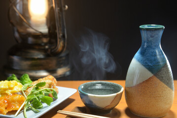 湯気の立ち昇る日本酒とランタン