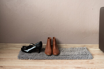 Brown ankle boots and black shoes on rug in entryway