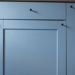 Minimalist kitchen cabinet door with a smooth blue surface and simple handle.