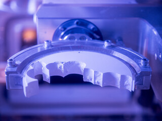 Cad cam machine milling zirconia dental prosthetics, modern digital dentistry manufacturing technology in high-tech automated laboratory for precision oral restoration.