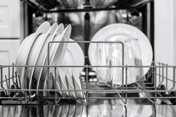 Dishwasher interior filled with clean plates and glasses, showcasing organized kitchenware in a...