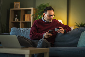 Man making secure online payment with smart phone and credit card at home