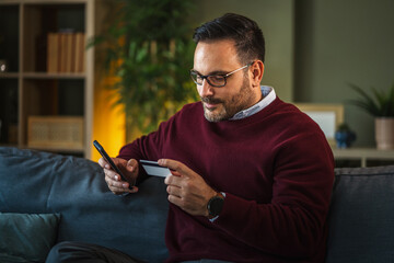 Man making secure online payment with smart phone and credit card at home