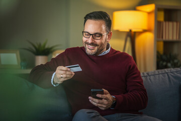 Man making secure online payment with smart phone and credit card at home